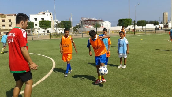 Our volunteer Jamie practicing football with a group of local kids. 